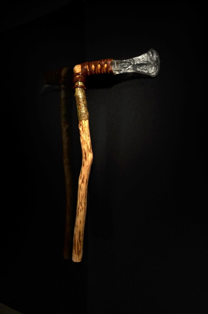 A large wooden handle., at the top is an L shape with leather binding which contains a glass axe