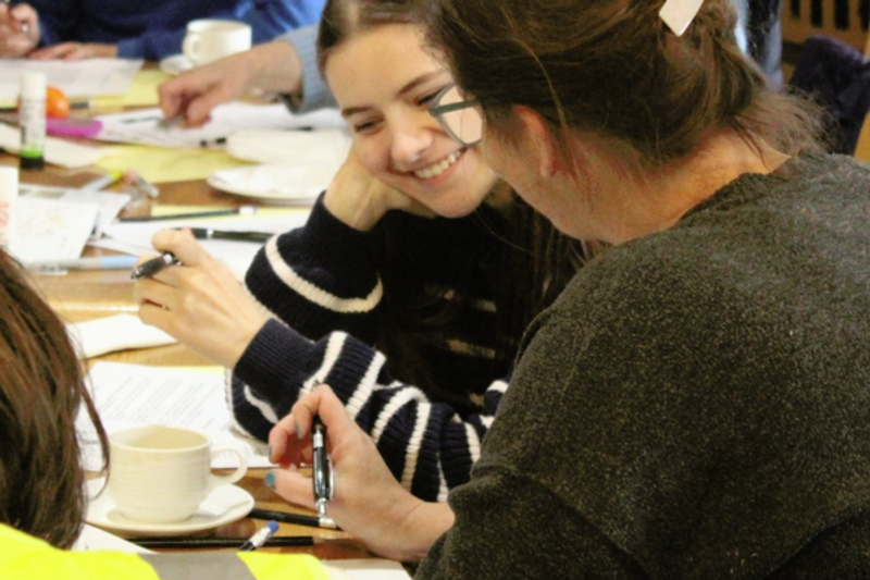 A person smiling at another person while participating in a workshop.