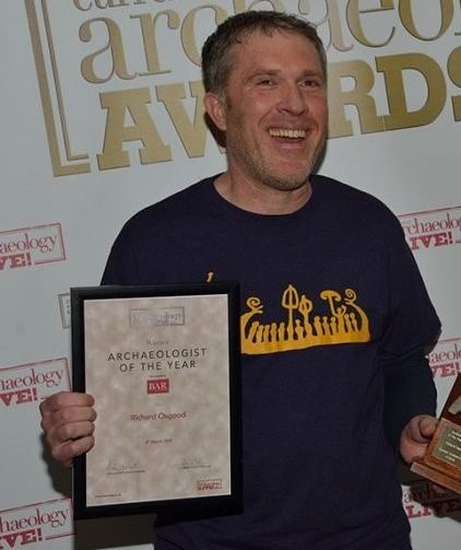 A person in a blue t shirt holding a plaque