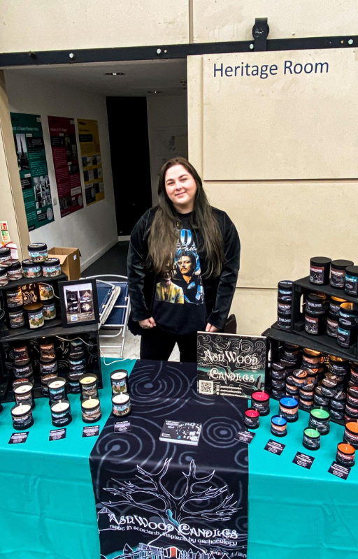 A person standing in front of a table with many jars of candles