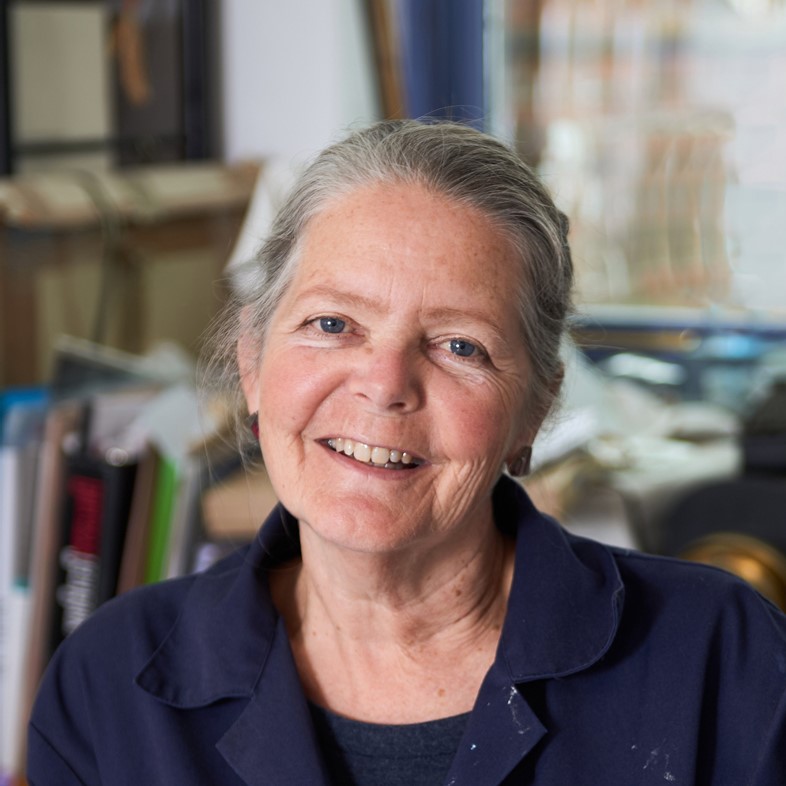 Photograph of a woman with her hair tied back, they are smiling