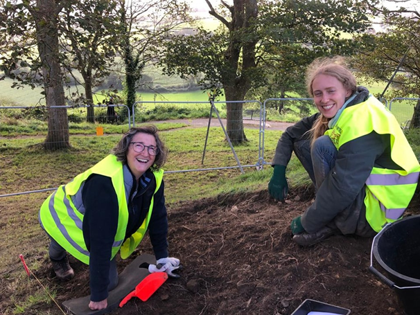 Two people smiling whilst digging
